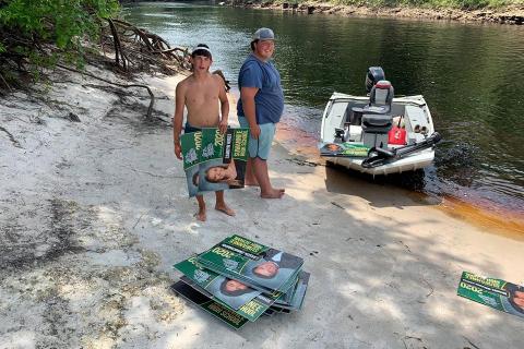 Boaters Shane McCoy and Will Griner are pictured with  the stack of signs they recovered from the Suwannee on Thursday. (COURTESY SCSO)