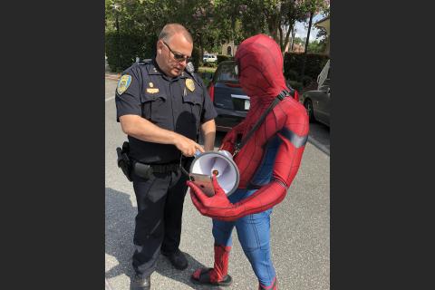 LCPD Assistant Chief Gerald Butler shows Spiderman, aka Todd Franklin, how to work the bullhorn the department lent him for a protest. (ROBERT BRIDGES/Lake City Reporter)