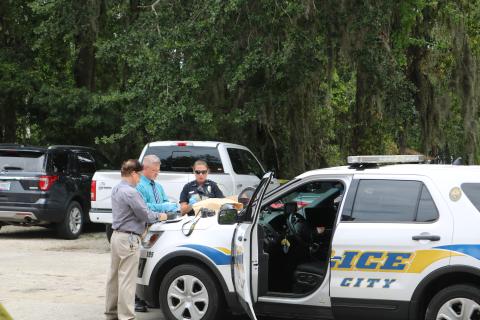 Phil Dorris, LCPD evidence technician (from left), Lt. Andy Miles and Officer Erica Bass count stolen money from the Ameris Bank robbery Wednesday morning. The loot was recovered after a suspect was apprehended about a block south of the bank. (TONY BRITT/Lake City Reporter)
