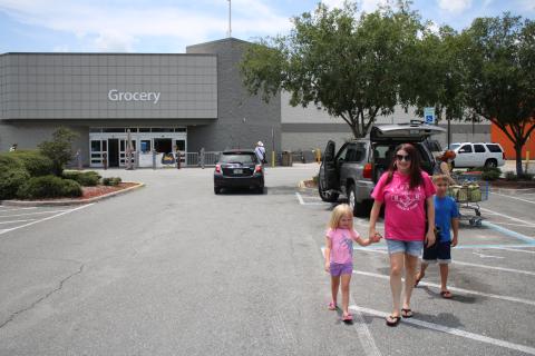 Jordyn Fletcher, 4, walks in the Lake City Walmart Super Center parking lot with Rebecca Fletcher and Jayden Fletcher, 9, Wednesday afternoon while the family was shopping at Walmart without masks. On Wednesday Walmart and Sam’s Club announced that effective July 20, customers will be required to wear face coverings when shopping at its stores. (TONY BRITT/Lake City Reporter)