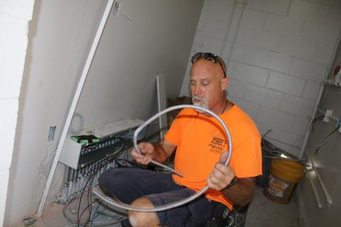 David Warren, a Wood’s Electrical Services employee, installs electrical wires in the Summers Elementary School kitchen Wednesday afternoon. The kitchen was recently gutted and will be updated for when students return to school. It’s the first major renovation project on the school’s kitchen in the past 25 years. (TONY BRITT/Lake City Reporter)