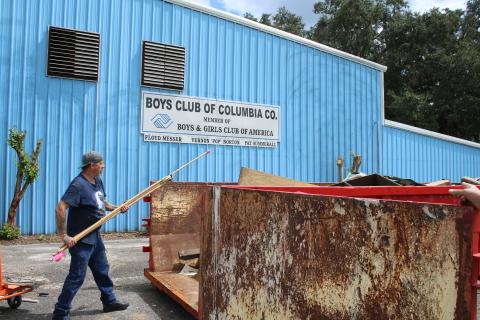 Scott Boisvert throws debris into a dumpster Thursday afternoon while cleaning out the old Boys Club of Columbia County facility. (TONY BRITT/Lake City Reporter)