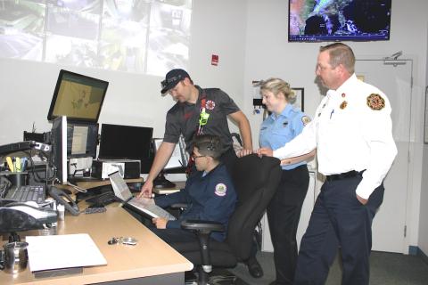 Dispatcher Marcel Ferro (seated) uses a backup code book to explain the Lake City Fire Department’s new Fire Priority Dispatch System that went online Wednesday. Firefighter Matt Herndon, (left) Communication Supervisor Megan Hollis and LCFD Assistant Chief Joshua Wehinger look on. The new fire and rescue dispatch system trains dispatchers on how to gather more pertinent information from 911 callers quickly and pass it along to responding fire and rescue first responders. (TODD WILSON/Lake City Reporter)