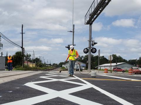 Crews finish work on the dynamic envelopes — giant connecting white X’s — at the rail crossing on U.S. Highway 129 (Ohio Avenue) in downtown Live Oak. The crossing reopened Monday night after being closed for two weeks for the improvements, which are part of the Florida Department of Transportation’s Operation STRIDE. (COURTESY FDOT)