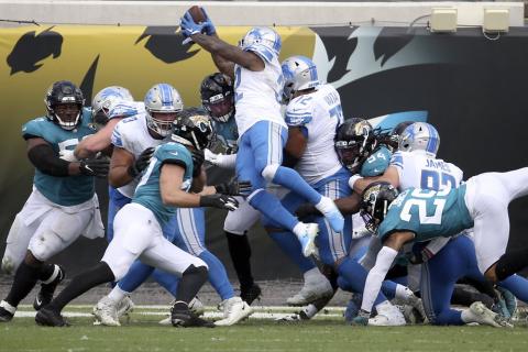 Detroit Lions running back D'Andre Swift (32) leaps over Jacksonville Jaguars linebacker Myles Jack (44) and defensive tackle Taven Bryan (90) for a touchdown on Sunday in Jacksonville. (PHELAN M. EBENHACK/Associated Press)