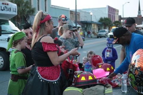 Trick-or-treaters receive candy from the Live Oak Fire Department’s booth at the Candy Carnival in downtown Live Oak last year. This year the city’s Community Redevelopment Agency is helping to sponsor a drive-in event at Heritage Park and Gardens. (SUWANNEE DEMOCRAT)