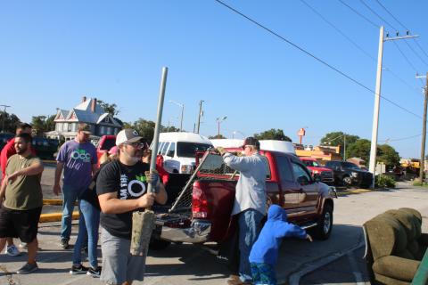 Chip Parker carries a pole to a trash dumpster, while other volunteers unload a truck, during Saturday’s Clean Lake City event. (TONY BRITT/Lake City Reporter)