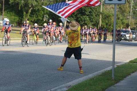 Zak Jones with the North Collier Fire Department waves an American flag Wednesday evening as dozens of Brotherhood Ride cyclists end their week-long trek across Florida at the Live Oak Fire Department station. The Brotherhood Ride is an annual bike ride to honor first responders who died in service. Former Suwannee County Fire Chief James Sommers was among those honored this year. Sommers died in August 2019. (JAMIE WACHTER/Lake City Reporter)