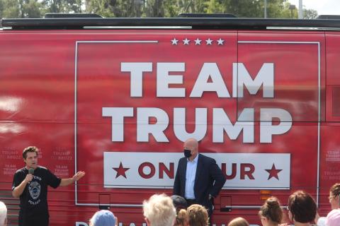 Matt Gaetz, a congressman from Florida’s First District in the panhandle, speaks during Monday’s rally in front of the Trump campaign bus while former acting U.S. Attorney General Matthew Whitaker looks on. More than 150 people attended the campaign stop at the Lake City Plaza. (TONY BRITT/Lake City Reporter)