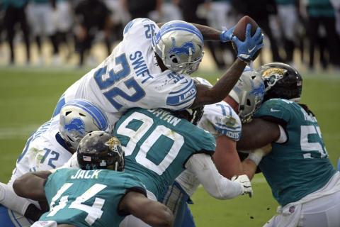 Detroit Lions running back D'Andre Swift (32) leaps over Jacksonville Jaguars linebacker Myles Jack (44) and defensive tackle Taven Bryan (90) for a touchdown on Sunday i Jacksonville. (PHELAN M. EBENHACK/Associated Press)