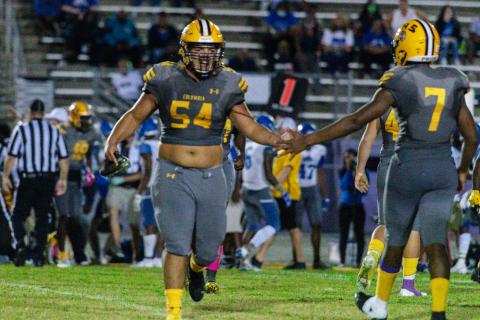 Columbia defensive lineman Jaycob Jones high fives defensive lineman A’deon Farmer as he comes in for a play against Lee last Friday. (RAY CARPENTER PHOTOGRAPHY)