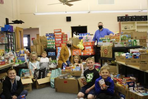 Columbia City Elementary students James Thomas (from left), Reese Wilson, Brantley Robinson, Olivia Medeiros, Hunter West and Luke Jordan show off food donations collected with Vickie Tuell, CCE guidance counselor, and Jonathan Jordan, CCE principal. (TONY BRITT/Lake City Reporter)