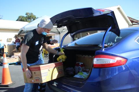 Jared Fraze, a Covenant Community School student, puts bags of food into a client’s car during Thursday’s Catholic Charities Thanksgiving basket giveaway. (TONY BRITT/Lake City Reporter)