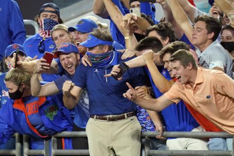Florida head coach Dan Mullen, center, celebrate with fans in the stands after the Gators defeated Georgia on Nov. 7 in Jacksonville. (JOHN RAOUX/Associated Press)