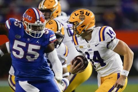 LSU quarterback Max Johnson (14) scrambles past Florida defensive lineman Kyree Campbell (55) on Saturday in Gainesville. (JOHN RAOUX/Associated Press)