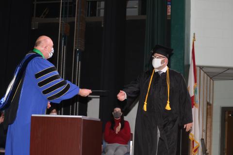 Lawrence Barrett (left), Florida Gateway College President, gives Kevin Doorman his water services bachelors degree during commencement exercises Thursday evening at the college. (TONY BRITT/Lake City Reporter)
