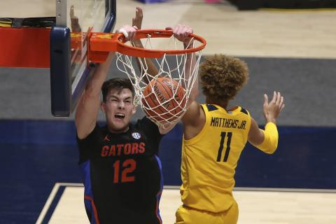 Florida forward Colin Castleton (12) dunks on West Virginia forward Emmitt Matthews Jr. (11) on Saturday in Morgantown, W.Va. (KATHLEEN BATTEN/Associated Press)