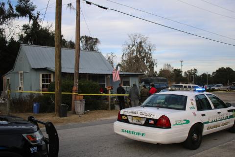 Lake City Police Officer Lt. Keith Heston (left) talks to a group of unidentified people at 179 NW Escambia Street, near the intersection of NE Calhoun Street, where a shooting occurred Wednesday afternoon. (TONY BRITT/Lake City Reporter)