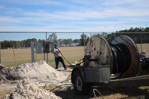 Jay Lambert pulls wire from a large spool while working on upgrades at the Florida Gateway Fairgrounds Rodeo Arena. The facility is adding more RV campsites for events. (TONY BRITT/Lake City Reporter)