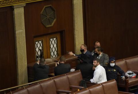U.S. Capitol police officers point their guns at a door that was vandalized in the House Chamber during a joint session of Congress on Wednesday in Washington, D.C. (DREW ANGERER/Getty Images/TNS)