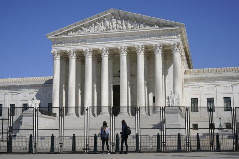 People view the Supreme Court building from behind security fencing on Capitol Hill on March 21 in Washington after portions of an outer perimeter of fencing were removed overnight to allow public access. A Supreme Court case being argued this week amid March Madness could erode the difference between elite college athletes and professional sports stars. (AP FILE PHOTO)