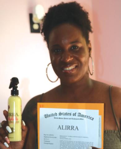 Shanekia Bing holds up one of her products along with a page from her U.S. trademark for her hair product line. (JAMIE WACHTER/Lake City Reporter)