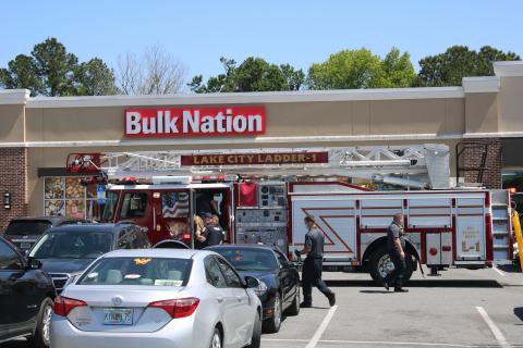 Officers walk with a man after they talked him down from the roof of Bulk Nation on Thursday afternoon. The man had been yelling and throwing clothes off the top of the building. (TONY BRITT/Lake City Reporter)