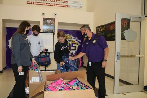 Stacy Albritton, DCF supervisor of Child Investigations (from left), stands with A.J. Kihei, Columbia High School student body president, Elijah Dockery, chairman of the Hope Bags Drive and Trey Hosford, Columbia High School principal, as they look at Hope Bags that will be donated to local children in foster care. (TONY BRITT/Lake City Reporter)