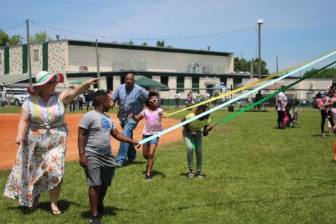 Elana Ramos (from left) points out to JaMarian Lane to watch how the ribbons are getting platted on the May Day pole during a NorthStar Family Resource Center May Celebration Saturday afternoon at Richardson Community Center. (TONY BRITT/Lake City Reporter)
