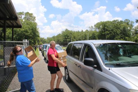 Alicia Blackford (left) and Laurie Renegar carry meals to a minivan Thursday afternoon at Five Points Elementary School. (TONY BRITT/Lake City Reporter)