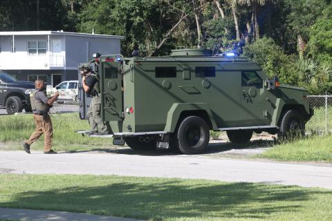 Law enforcement officers gather outside a building at the intersection of SW Main Boulevard and SW Ivan St. Monday afternoon after a man barricaded himself inside. (MORGAN MCMULLEN/Lake City Reporter)