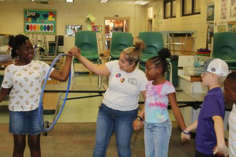 An unidentified child is passed a hula hoop from Columbia County Sheriff’s Office School Resource Deputy Nicole Martell during an activity during camp Tuesday. (TONY BRITT/Lake City Reporter)