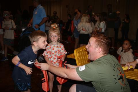Easton Helsel (left), 5, makes a face with Jacob English (far right) during the Christ Central Vacation Bible School session Wednesday night as Emery Helsel, 4, looks on while English gives them drawstring book bags. (TONY BRITT/Lake City Reporter)