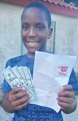 Ja’Marion West shows off his collected donations along with a list of those who helped him raise the $400. (COURTESY)