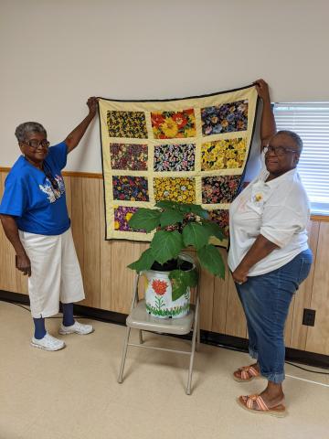 Oleatha Harris (from left) presented Gloria Bradley a Purple Angel Trumpet Plant and lap roll quilt for her service to the community and years of friendship. (COURTESY)