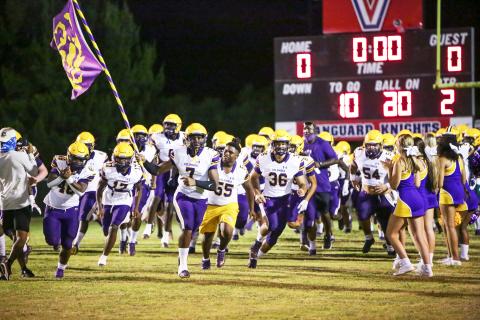 Columbia defensive end Adeon Farmer raises the team flag as he leads the Tigers onto the field prior to their Preseason Classic against Vanguard on Aug. 20. (BRENT KUYKENDALL/Lake City Reporter)