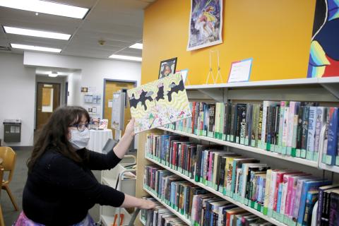 Columbia County Public Library Programming Specialist Emma Miles looks for a spot to display a piece of art. So far, 17 works have been submitted to this year’s Youth Art Contest. (TONY BRITT/Lake City Reporter)