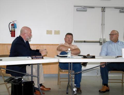 County Attorney Joel Foreman, left, reads the county charter off his phone Thursday after officials were informed their meetings in Fort White may be in violation. County Commissioners Tim Murphy, center, and Rocky Ford listen. (TONY BRITT/Lake City Reporter)