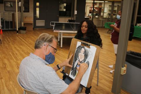 Clayon Wilson, Florida Gateway College volleyball coach, smiles as Dino Casterline draws her caricature during FGC’s first day of classes. (TONY BRITT/Lake City Reporter)