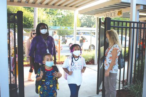Jeanette Young (far right), an Eastside Elementary School employee, welcomes kindergartners and their parents to campus for the first day of school. (TONY BRITT/Lake City Reporter)