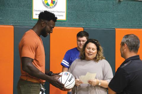 Former Gators basketball standout Patric Young (left) looks over a basketball signed by former members of the University of Florida team as Eli Stewart and Laura Lashley reminisce about Eli’s visit to a UF sports camp. (MORGAN MCMULLEN/Lake City Reporter)