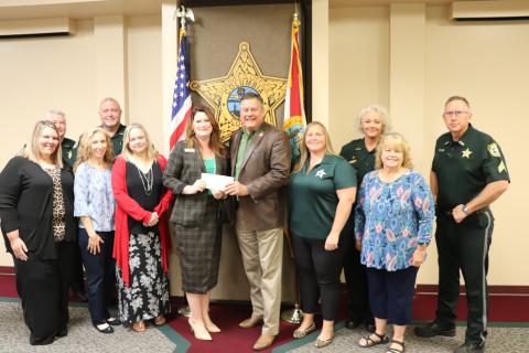 Columbia County Sheriff Mark Hunter, surrounded by other CCSO employees, presents Maria Knapp with the Florida Sheriffs Youth Ranch with a check of more than $58,000 from the agency’s annual ‘Fins-N’Pins’ fundraiser. (COURTESY/Columbia County Sheriff's Office)