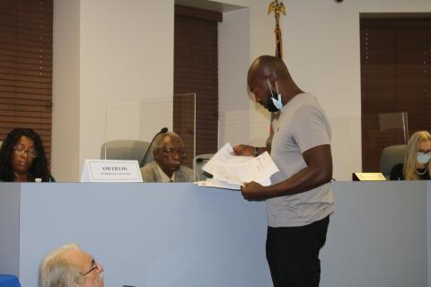 Community activist Sylvester Warren III hands out copies of his complaint to members of the Lake City Council at Tuesday’s meeting. (TONY BRITT/Lake City Reporter)