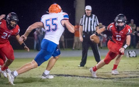 Fort White quarterback Clayton Philpot evades pressure from Branford linebacker Devin Mosley on Friday night. (CHRISTINA FEAGIN/Special to the Reporter)