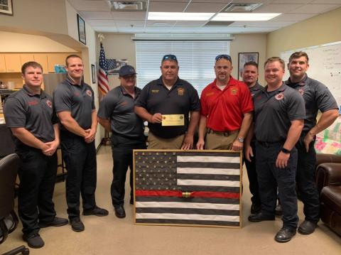 Suwannee County Fire Chief Eddie Hand (center) and Division Chief Matt Garbett present the Lake City Fire Department with a fire hose flag in memory of Chief Randy Burnham. (COURTESY)