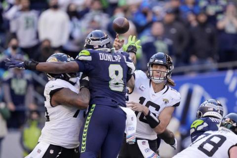 Seattle Seahawks defensive end Carlos Dunlap puts a hand up as he tries to deflect a pass from Jacksonville Jaguars quarterback Trevor Lawrence on Sunday in Seattle. (STEPHEN BRASHEAR/Associated Press)