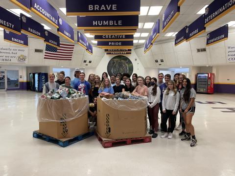 Students at Columbia High School gather around a pair of boxes containing donated canned and dry foods to be given to charity. (COURTESY)