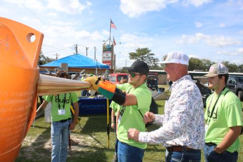 Ethan Humphries (center), a Branford High School student, uses gloves while getting tips from Eric Crawford, a Clay Electric line supervisor, during Wednesday’s Build My Future event. (TONY BRITT/Lake City Reporter)