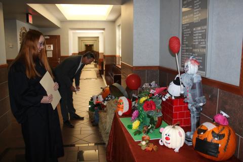 Several decorated pumpkins, including one that resembles Pennywise the Dancing Clown from the movie ‘It,’ sit in the lobby of the Columbia County Courthouse as Columbia County Judge Sara Carter (left) and Columbia County Clerk of Courts Jay Swisher examine entries. (TONY BRITT/Lake City Reporter)