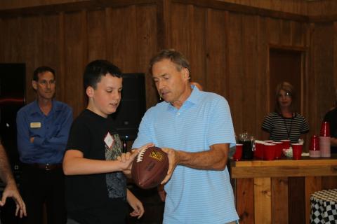 Lucas Gollery (left) gets a lesson from Jeff Kemp on how to hold a football properly. (TONY BRITT/Lake City Reporter)